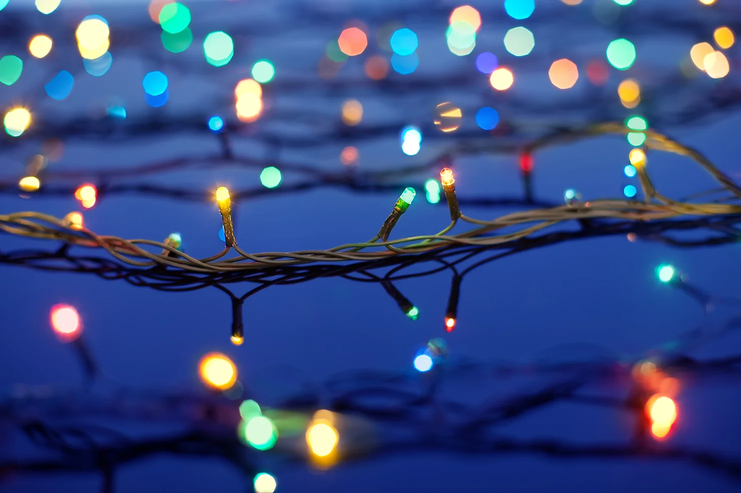 This image shows a close-up of colorful twinkling lights spread out against a blurry blue background, giving a festive or decorative atmosphere.