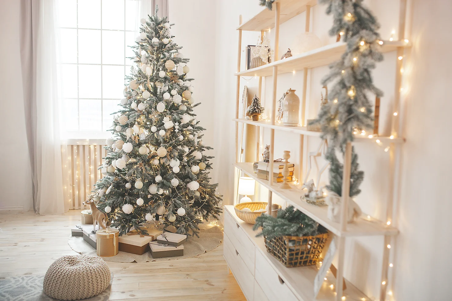 A cozy room decorated for Christmas with a decorated tree, gifts, and a lit bookshelf creating a warm, festive atmosphere.